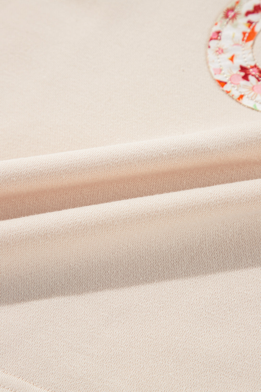 Haut à manches larges et coutures apparentes avec patch floral beige