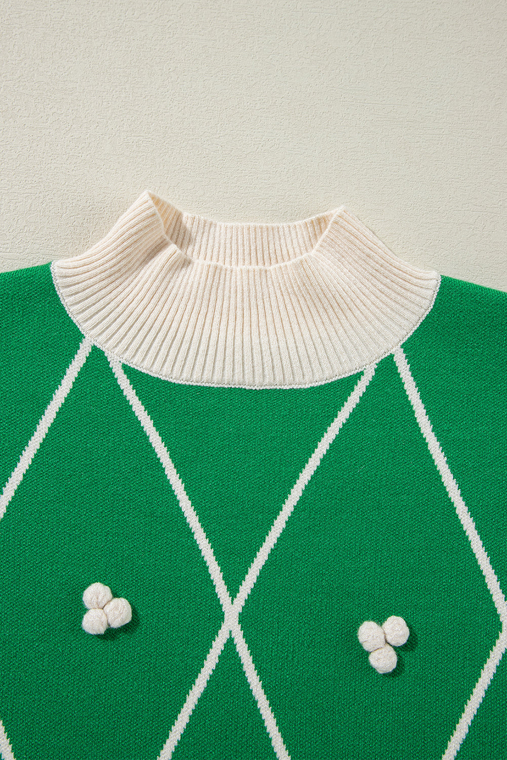 Pull col montant à motif losanges vert foncé avec pompons contrastés