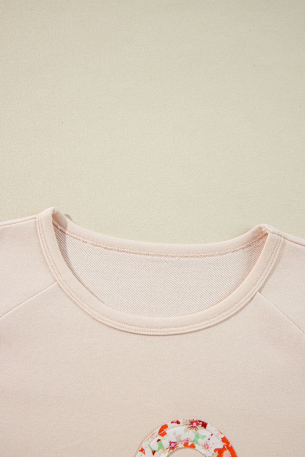 Haut à manches larges et coutures apparentes avec patch floral beige