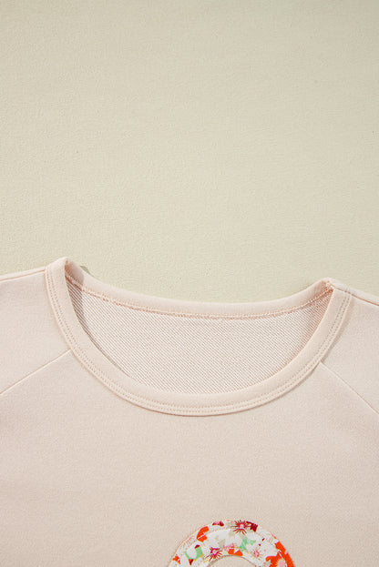 Haut à manches larges et coutures apparentes avec patch floral beige