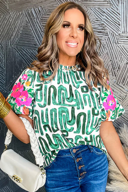 Haut imprimé vert noirâtre à manches bouffantes et col à volants