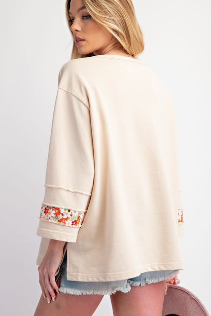 Haut à manches larges et coutures apparentes avec patch floral beige