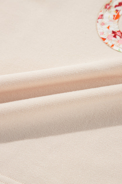 Haut à manches larges et coutures apparentes avec patch floral beige